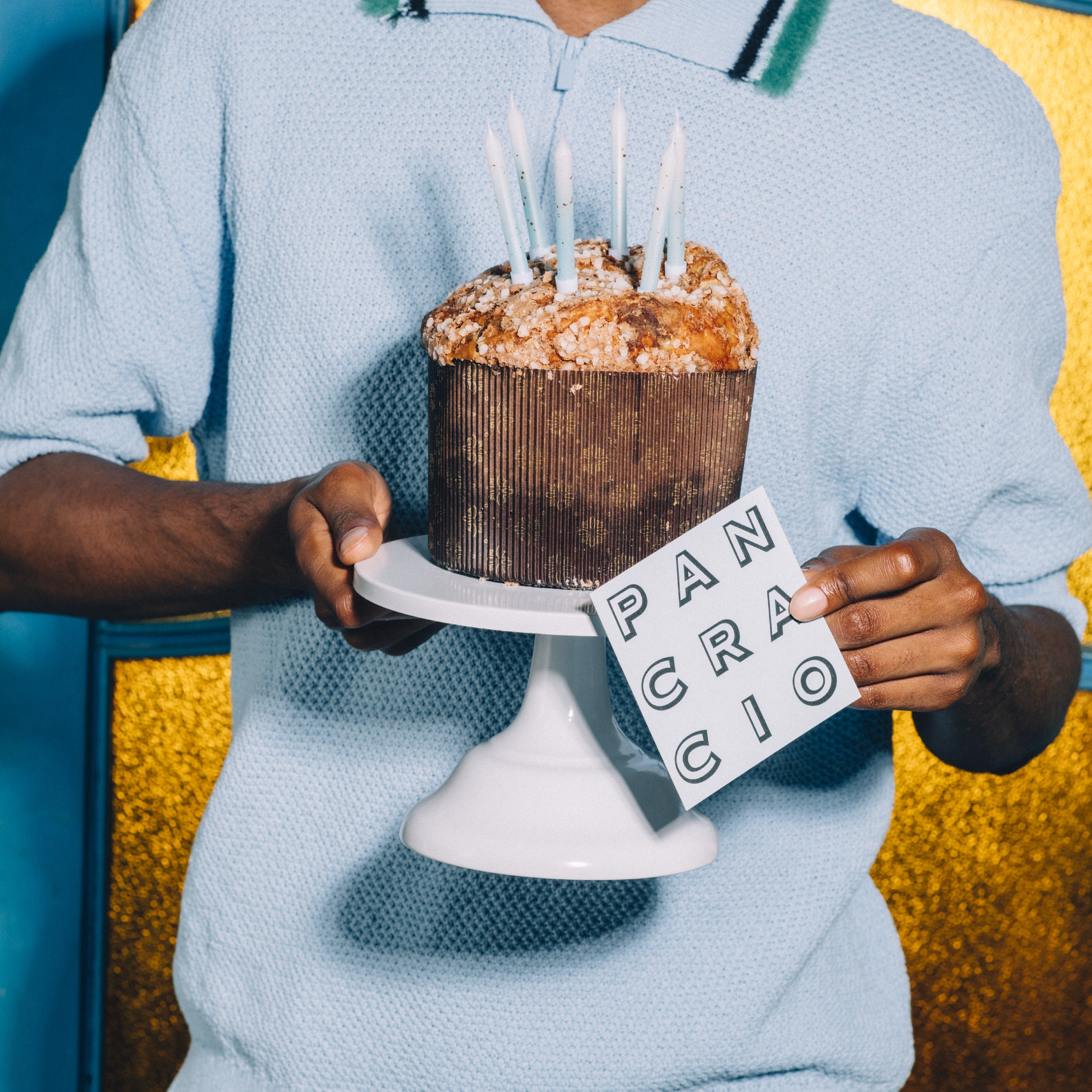 Una persona sosteniendo un panettone de chocolate negro con velas de cumpleaños.