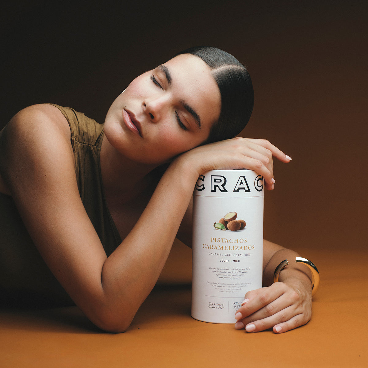 Una modelo posando con un tubo de Pistachos Caramelizados de Pancracio Chocolates.